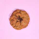 Sticky Toffee Pudding New York Cookie with gooey sticky toffee center on a pink background by Crumbs & Doilies.